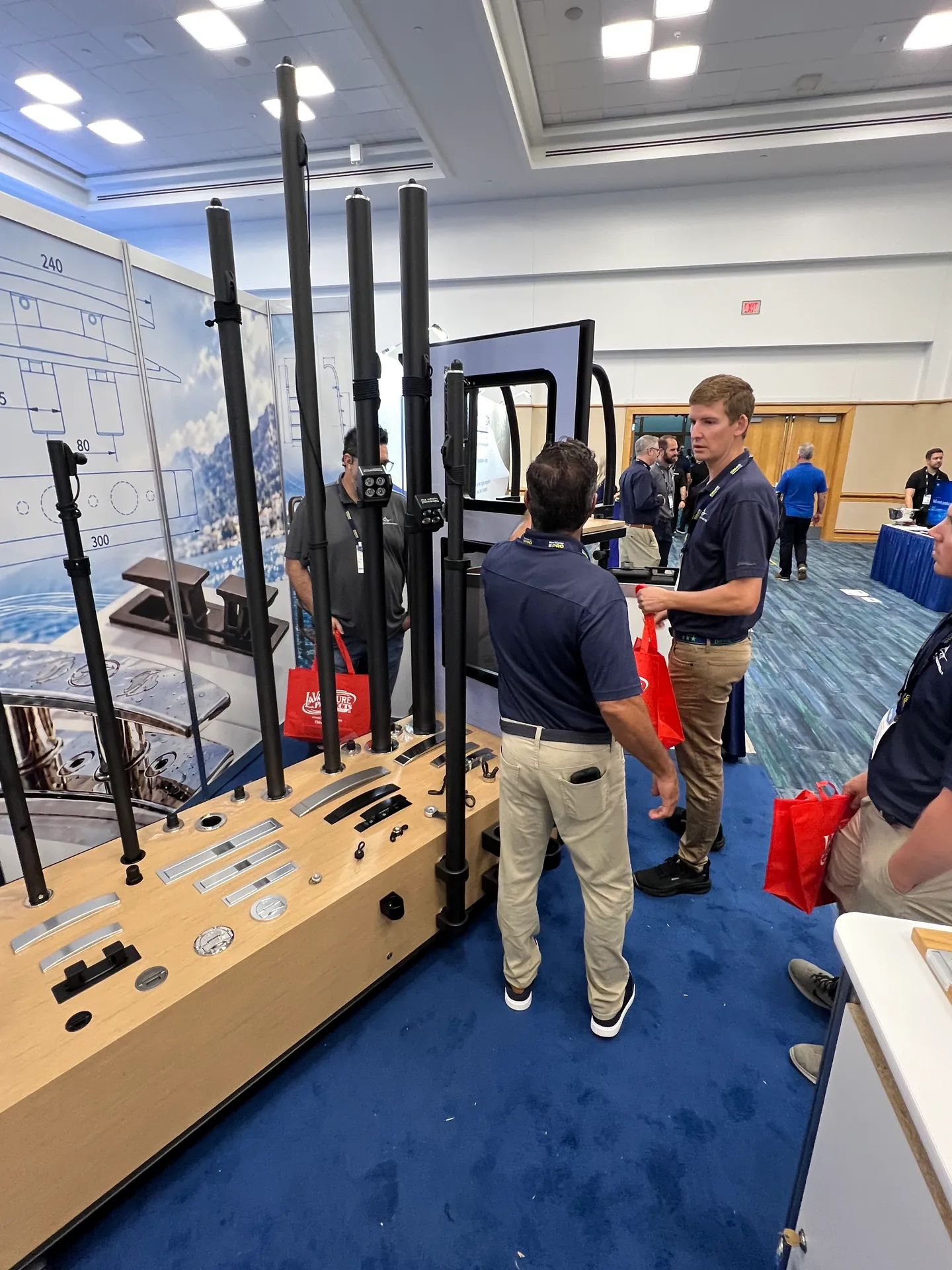 Visitors talking beside the marine hardware and awning pole display at the Yachtify stand.