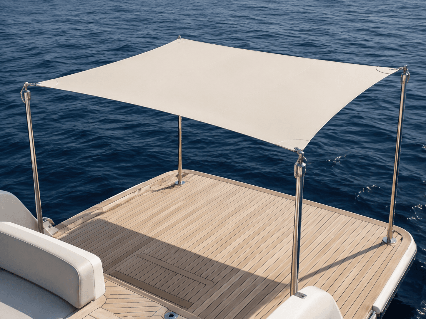 Product-type illustration of a canvas deck shade supported by four poles over a teak deck