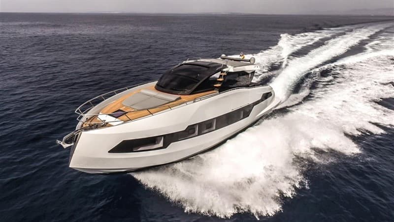 White motor yacht turning across dark blue water with a sweeping white wake.