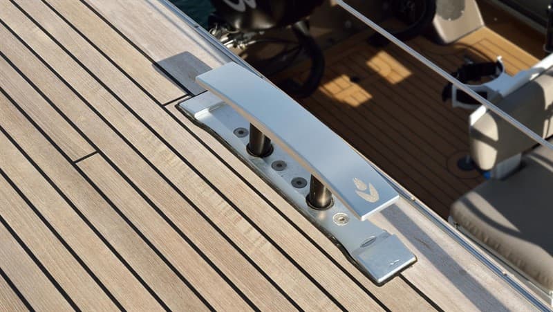 Raised polished cleat mounted beside teak deck planks.