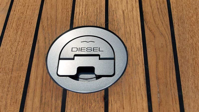 Circular metal diesel deck filler set flush into teak planks.