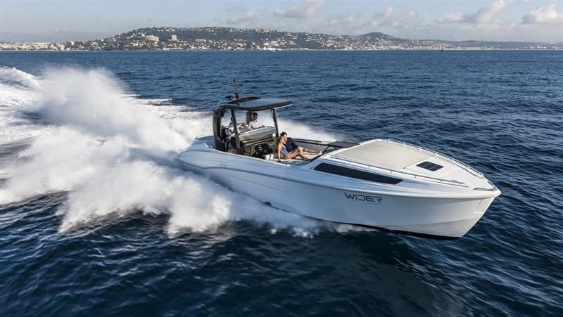 White open motorboat turning at speed with spray behind it.
